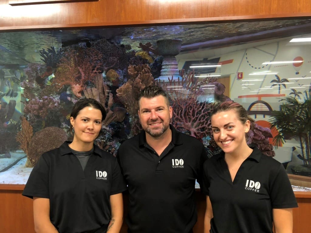Three people standing in front of a wall with fish.